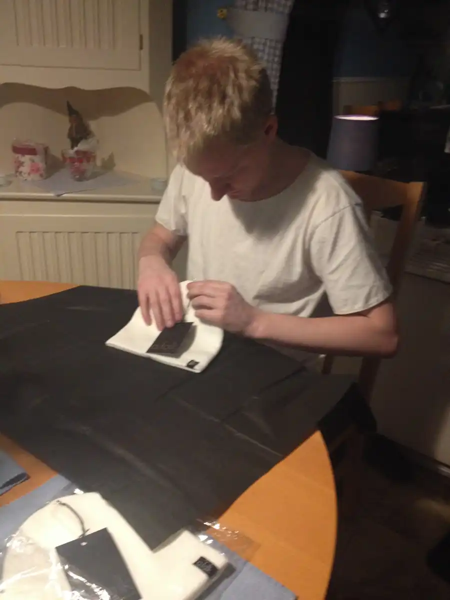 Andreas wraps a white beanie in silk paper in the kitchen