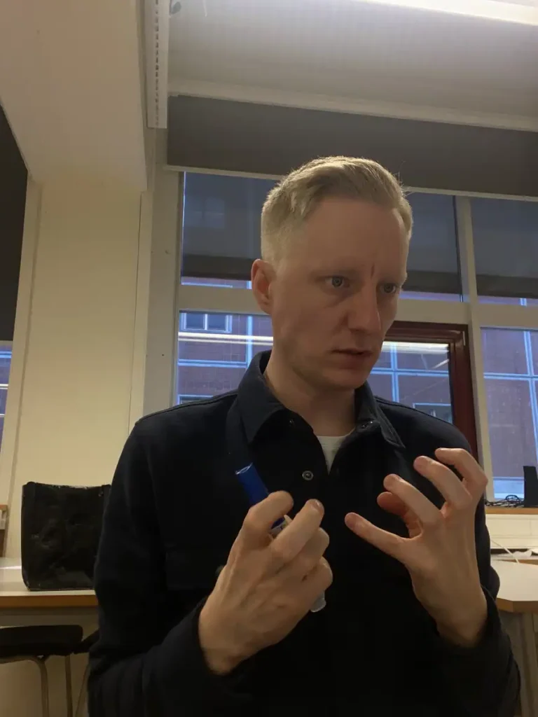 Andreas in the classroom with a pen in the hand feeling frustrated