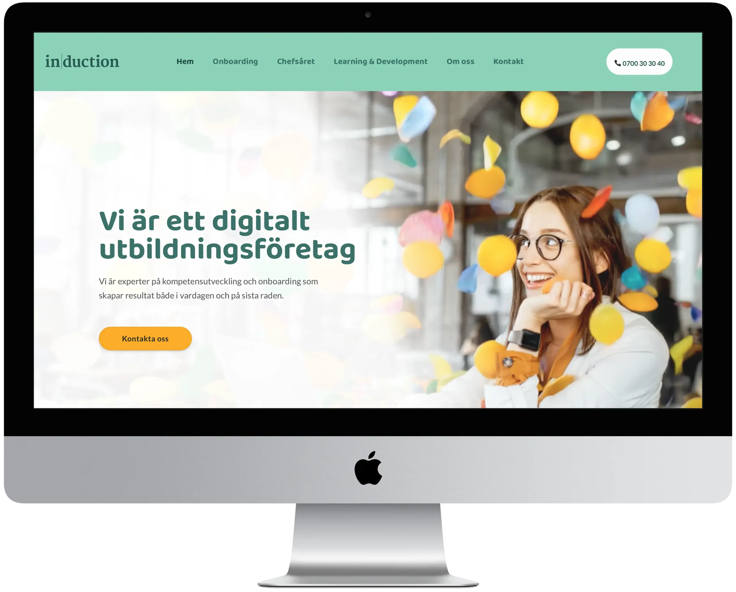 En iMac mockup som visar startsidan av Inductions nya hemsida.